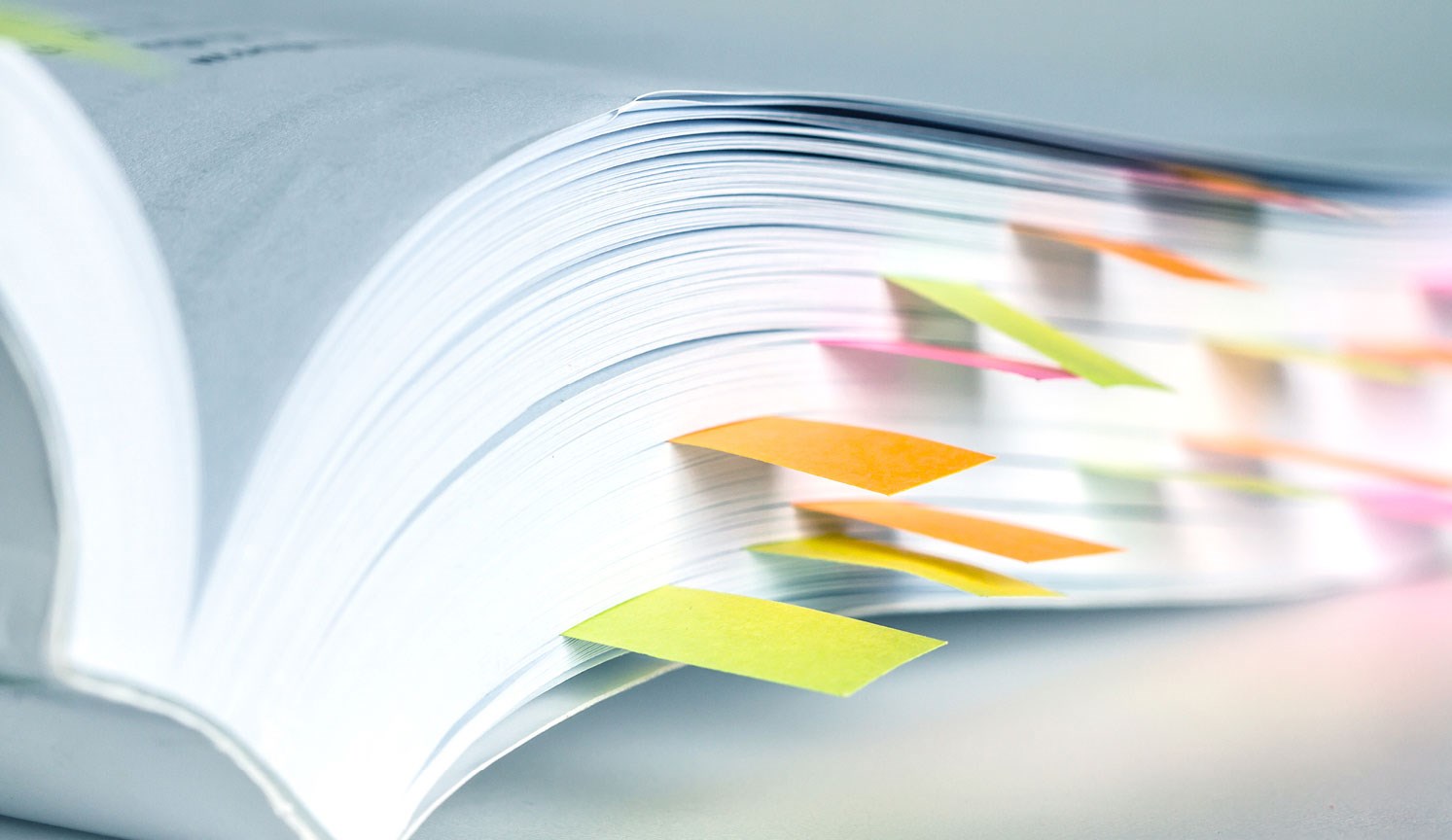 close up of the end of an opened reference book with multi coloured sticky bookmarks